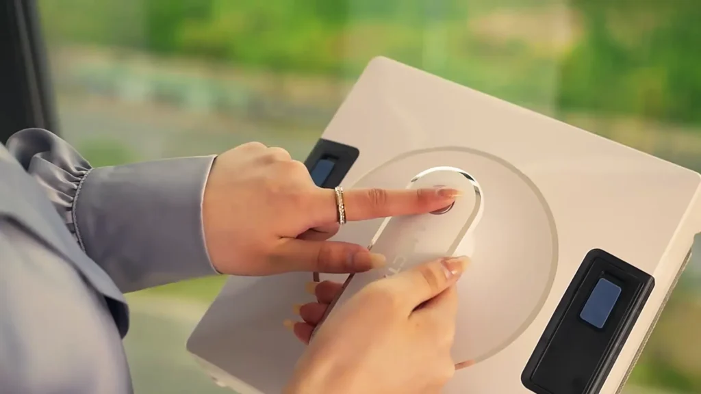 Utilisateur appuyant sur le bouton d’un robot lave-vitre